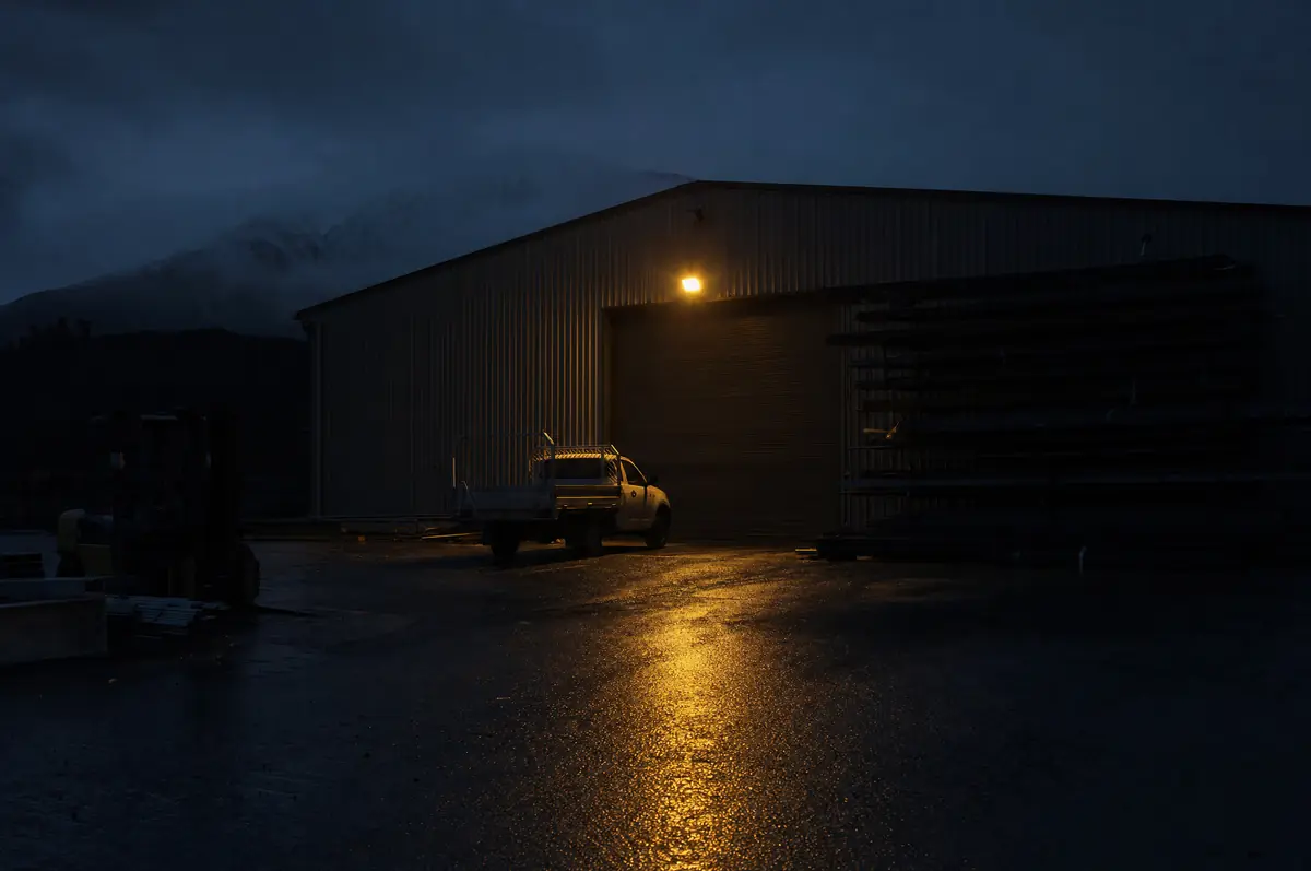 An empty workshop yard at night, one ute left